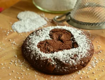 chocolate cookie with a heart-shaped design dusted with powdered sugar